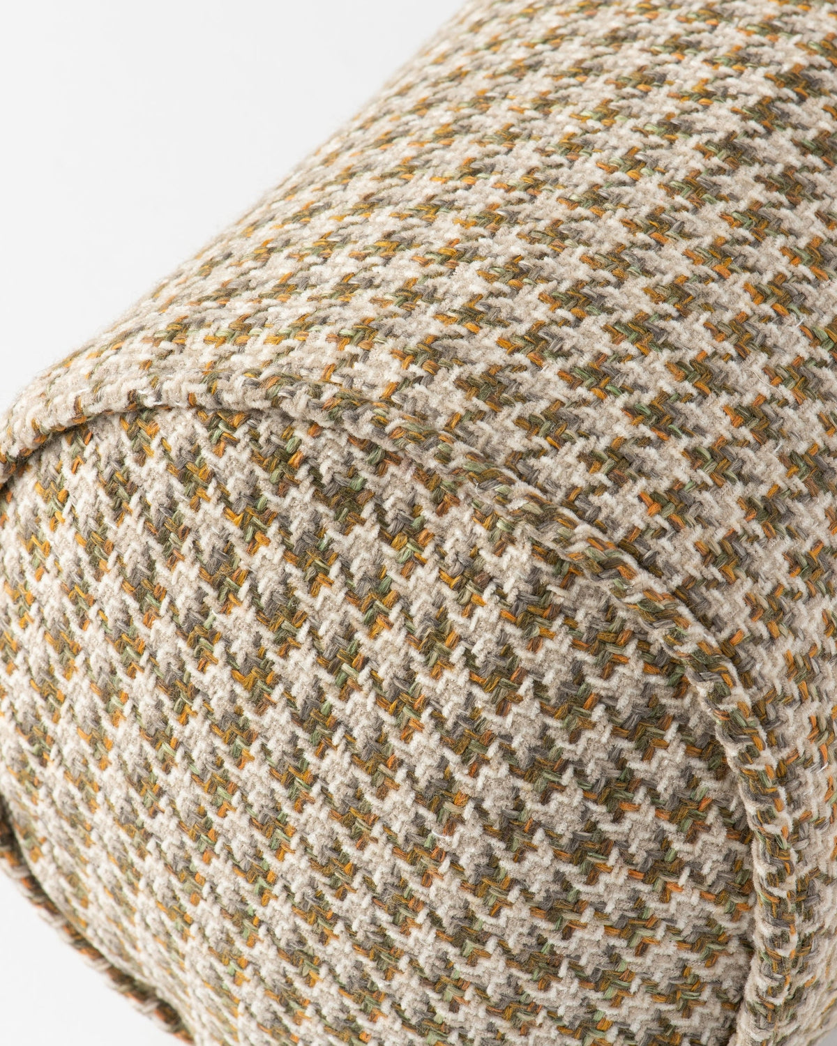 Close-up of a woven textile with a houndstooth-like pattern in beige, olive green, and small orange-brown flecks, showing the fabric texture and stitching.