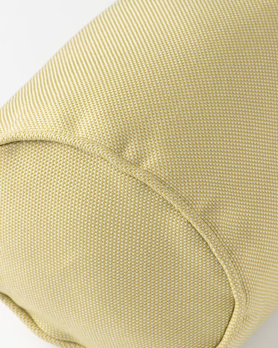 Close-up of a light olive green woven fabric cylindrical cushion or bolster with a rounded seam.