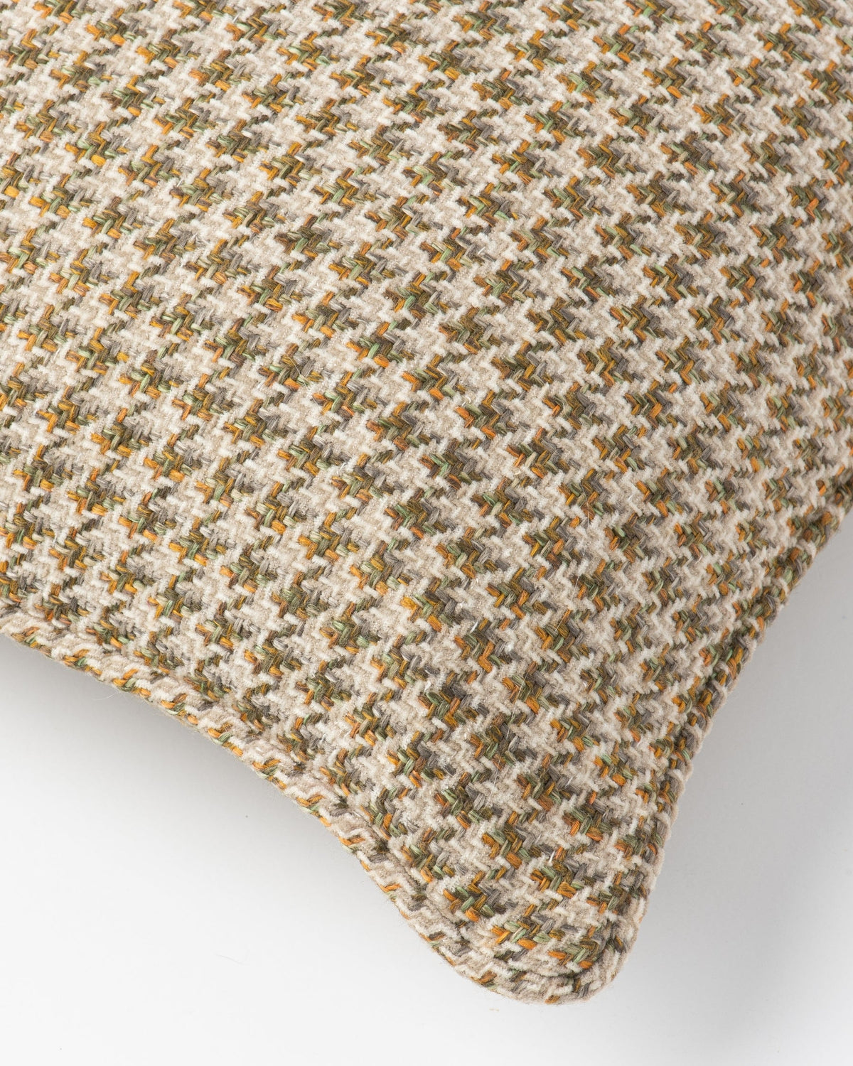 Close-up of a woven throw pillow cover featuring a textured houndstooth pattern in beige, brown, and muted green.
